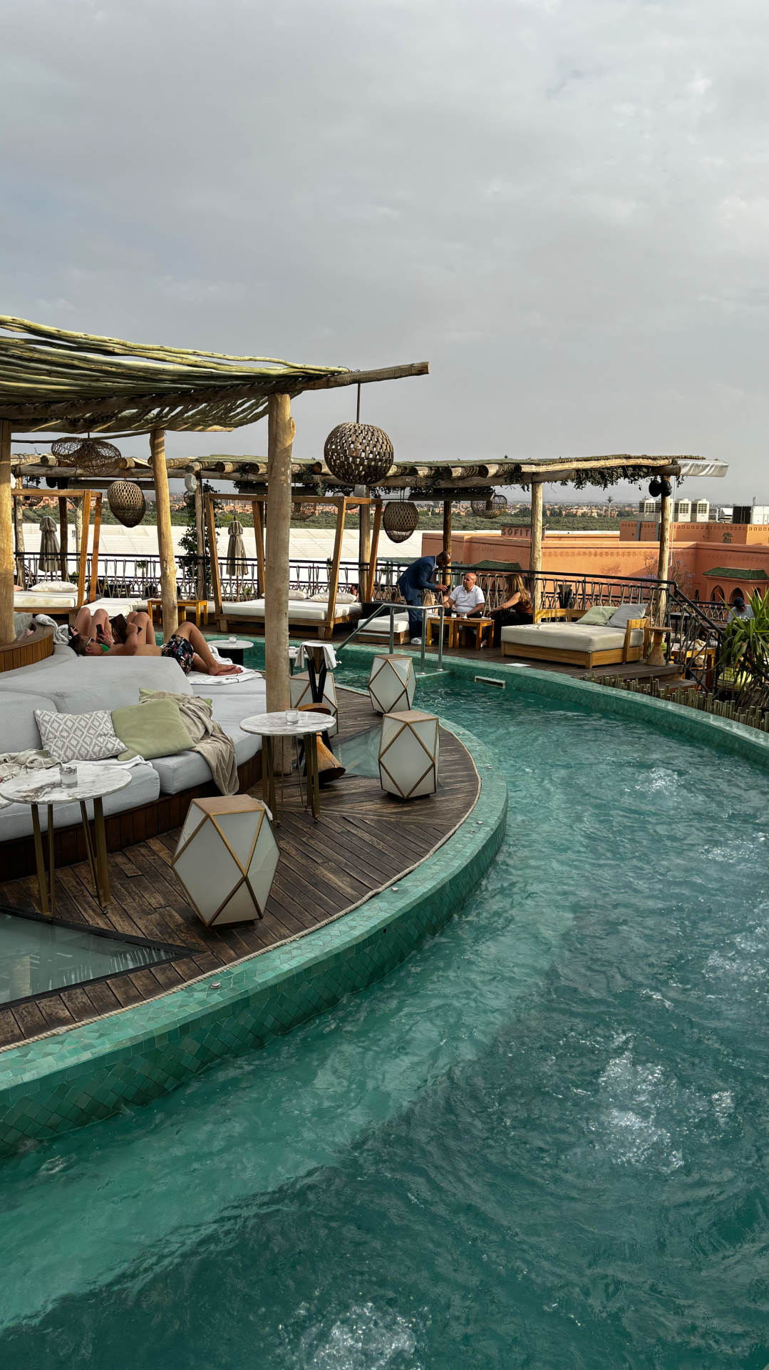 Piscine rooftop du Nobu Hotel Marrakech avec pergolas en bois, vue sur la ville et l’Atlas au loin