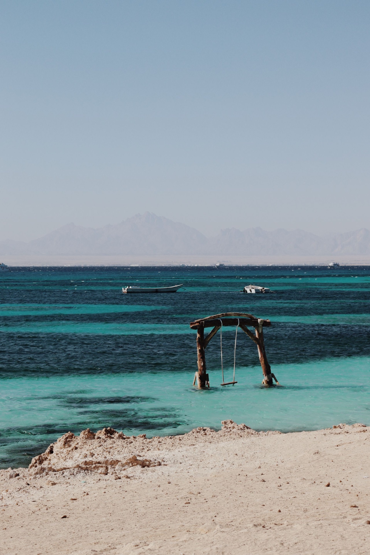 Mer Rouge turquoise à Hurghada, montagnes arides et bateaux au premier plan