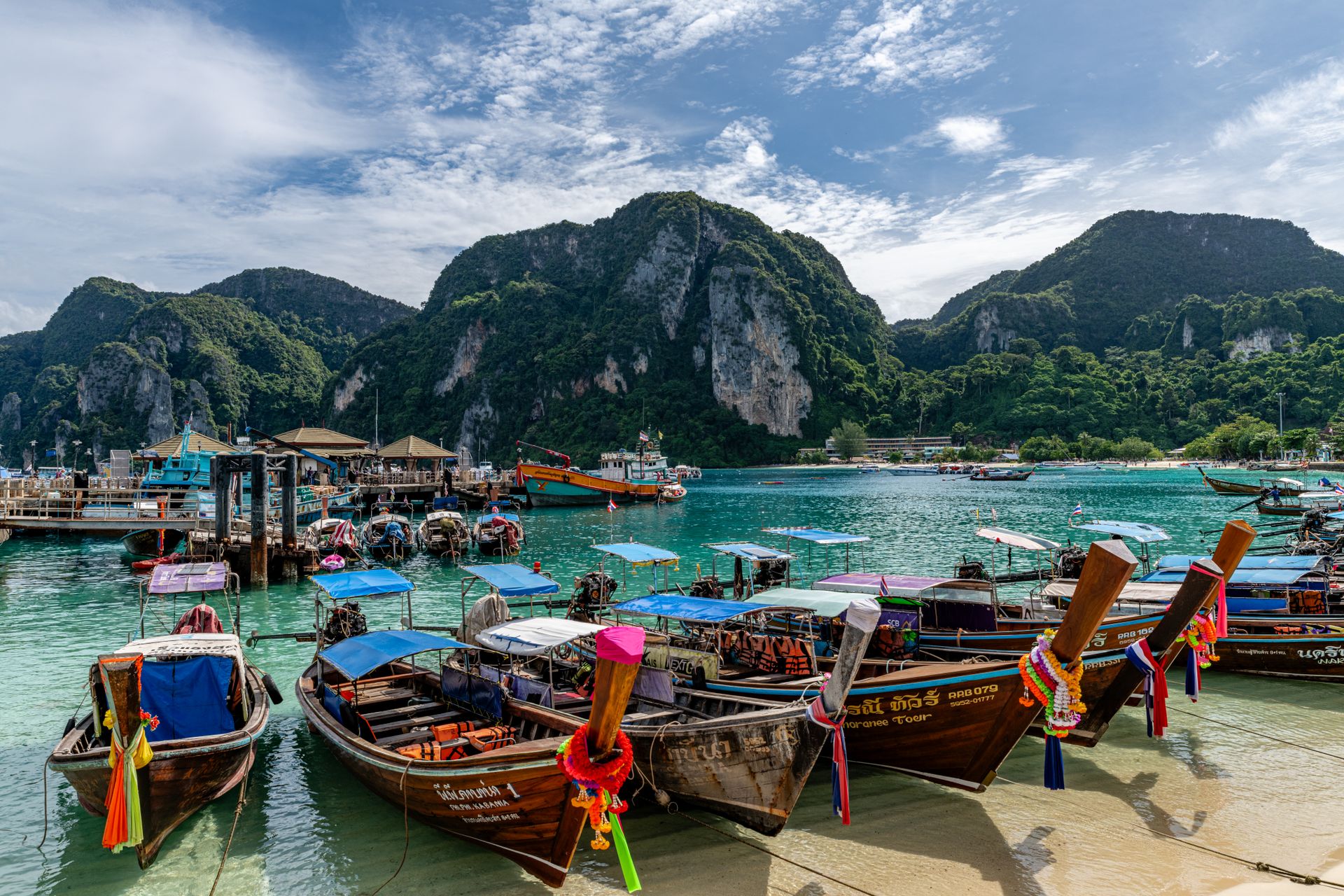Bateaux long-tail traditionnels amarrés dans une crique de Phuket, falaises calcaires en arrière-plan